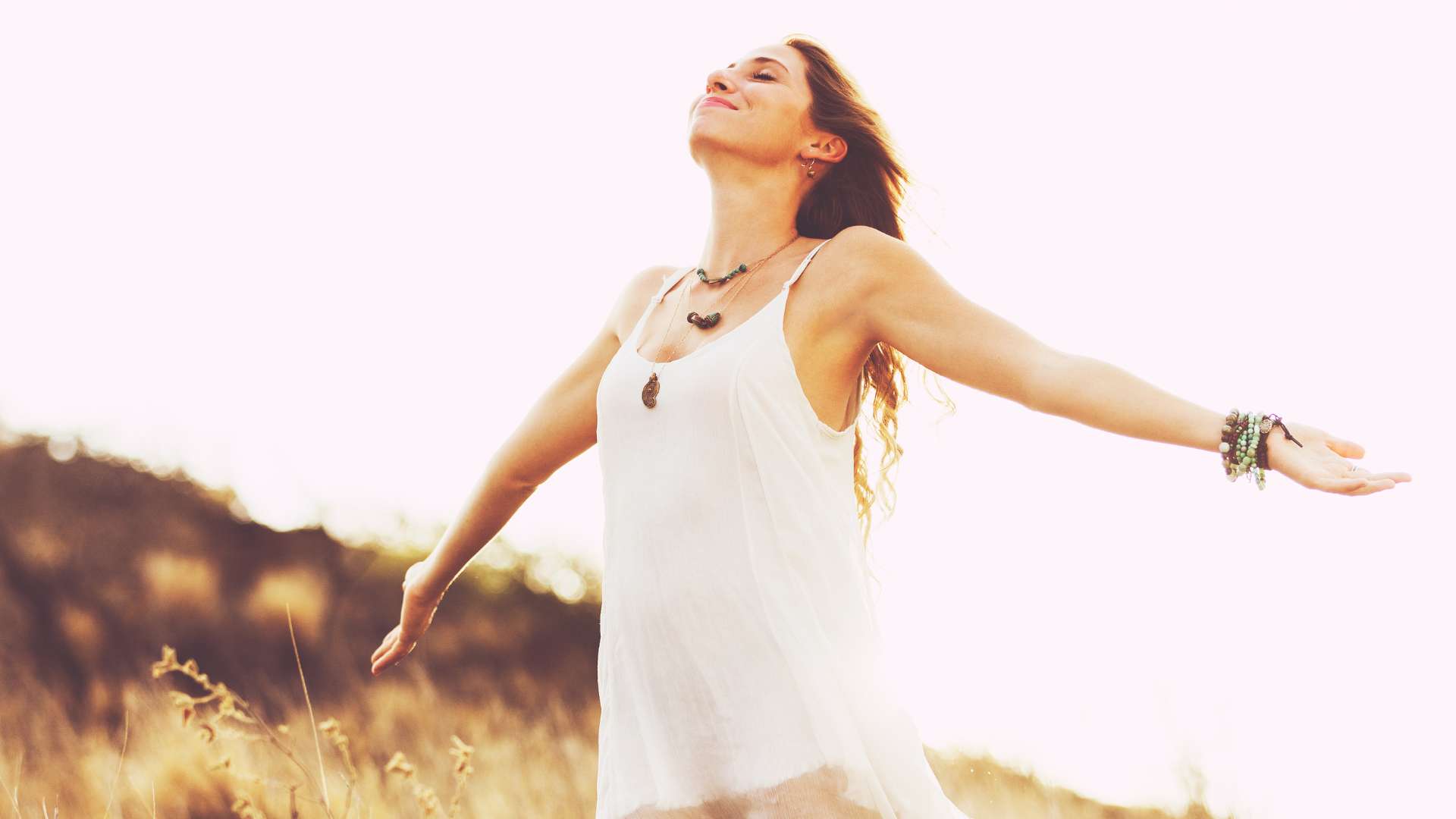 A woman standing outdoors in a sunlit field, conveying hope and recovery from depression