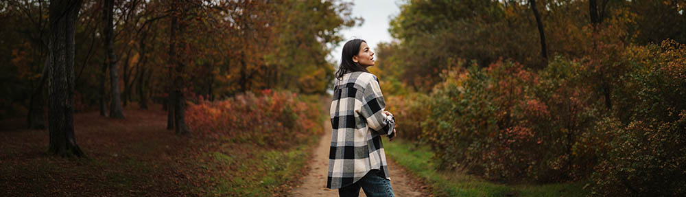 Person walking a quiet forest path, looking back, representing steady progress with treatment-resistant depression